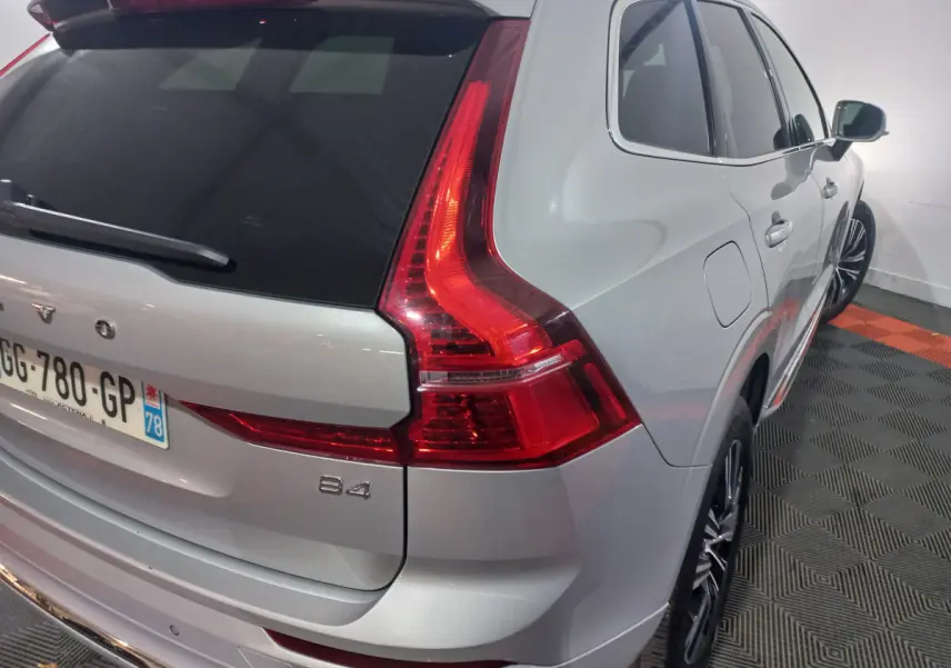 Vue 3/4 arrière droite d'un Volvo XC60 B4 gris clair avec feux arrière LED et jantes alliage noires.