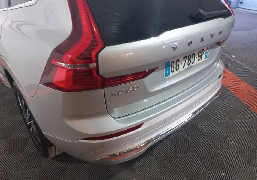 Vue 3/4 arrière droite du Volvo XC60 gris clair avec feux arrière LED et plaque d'immatriculation française visible.