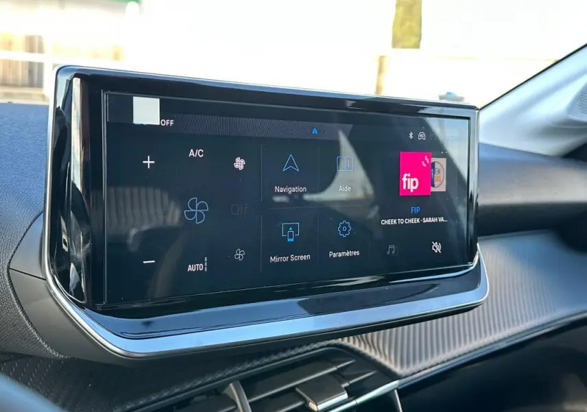Écran tactile du tableau de bord de la Peugeot 208 Hybrid 110 blanc, vue rapprochée côté passager.