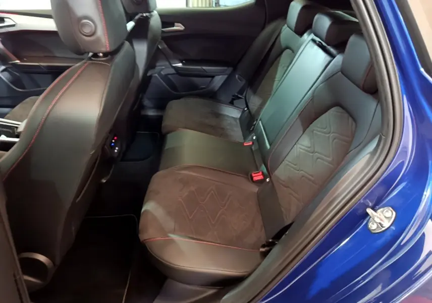 Vue intérieure côté droit sur la banquette arrière en cuir noir avec surpiqûres rouges d’un SEAT Leon bleu 2021.