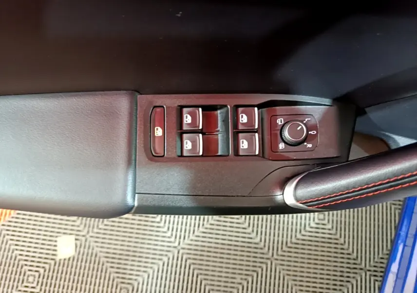 Gros plan sur les commandes de lève-vitres et réglage des rétroviseurs côté conducteur d’une SEAT Leon bleu 2021.