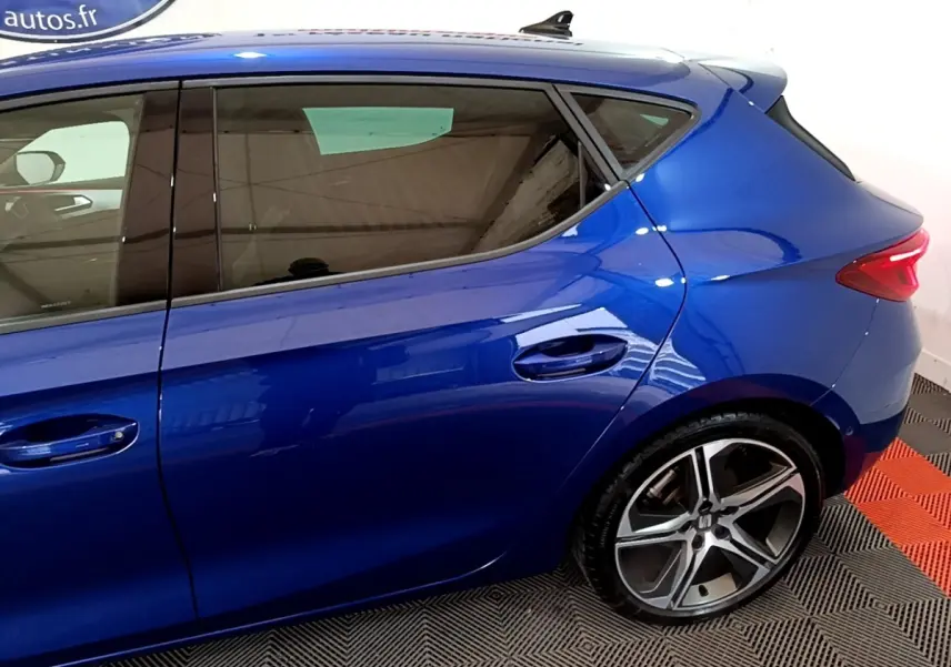 Vue latérale droite d'une SEAT Leon bleu électrique, mettant en valeur les jantes alliage et les vitres teintées.
