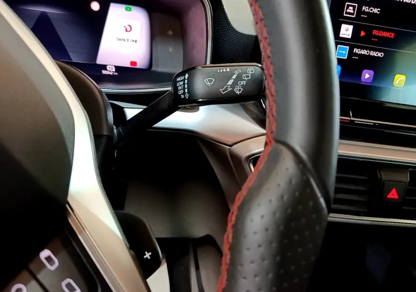 Gros plan intérieur sur le volant cuir noir avec surpiqûres rouges et le combiné d'instruments digital du SEAT Leon 2021.