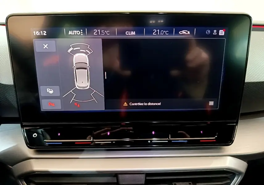 Écran tactile central du tableau de bord du SEAT Leon 1.5 eTSI bleu, affichant l'aide au stationnement.