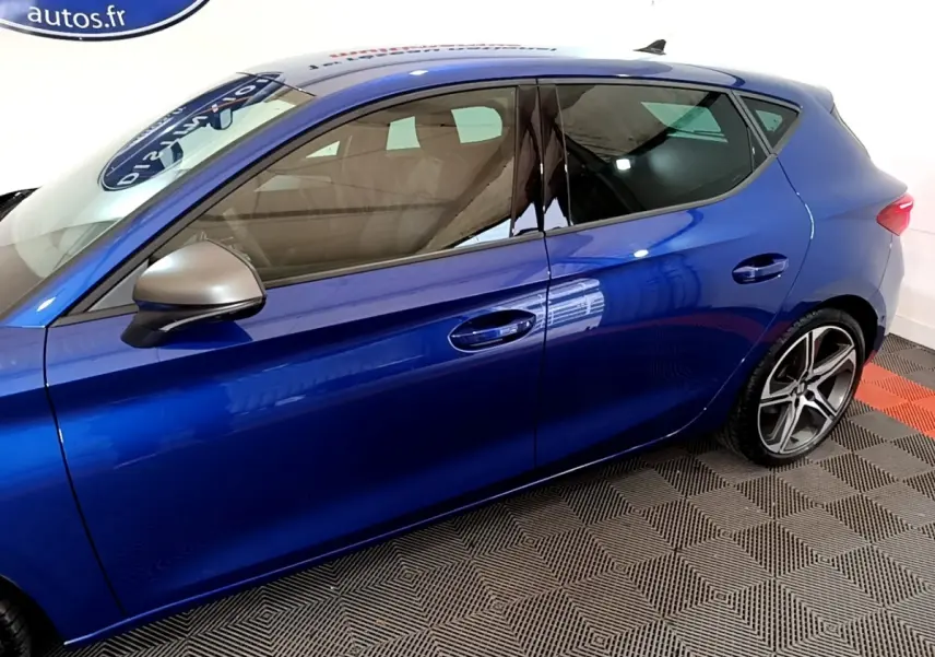 Vue latérale gauche d'une SEAT Leon bleu métallisé avec rétroviseur argent et jantes alliage sport.