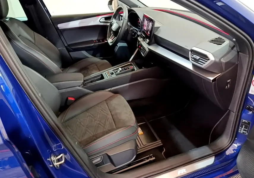 Intérieur de la SEAT Leon bleu, vue côté droit, avec sièges noirs et tableau de bord moderne à écran tactile.