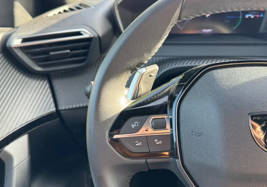 Gros plan sur le volant noir du Peugeot 2008 Hybrid 136 e-DCS6 Allure avec commandes intégrées et tableau de bord partiellement visible.