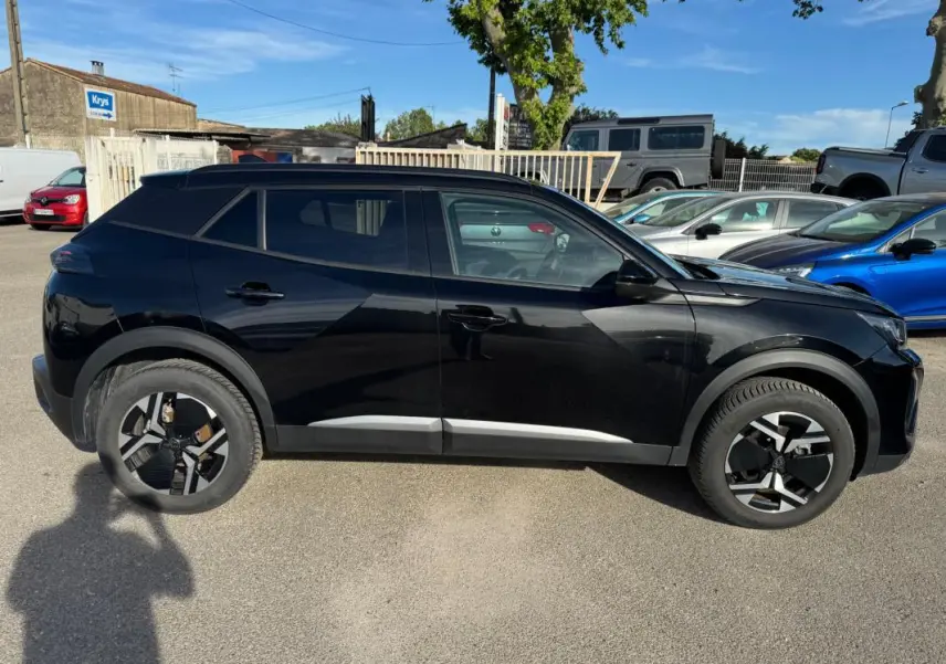 Peugeot 2008 Hybrid noir vue de profil côté gauche, avec jantes alliage 17 pouces et barres de toit visibles.