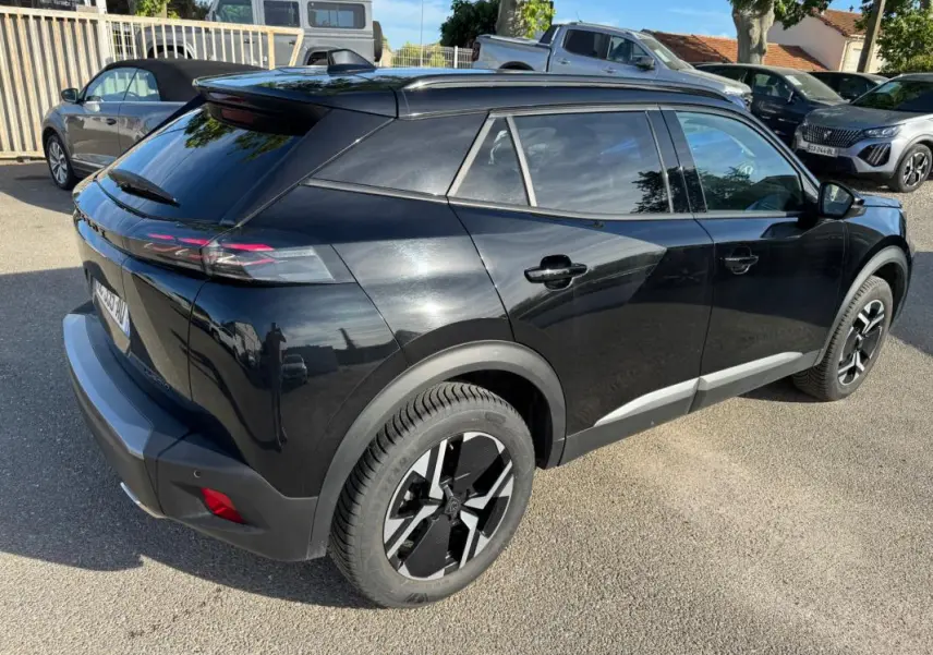 Peugeot 2008 Hybrid noir vue 3/4 arrière droit, avec barres de toit et jantes alliage 17 pouces visibles.