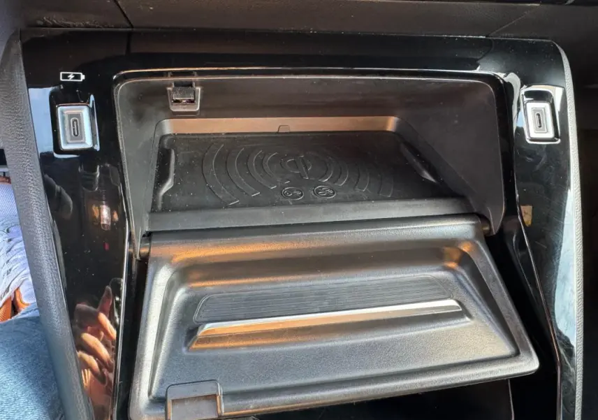 Détail de la console centrale noire du Peugeot 2008 Hybrid 136 avec compartiment de rangement et chargeur sans fil.
