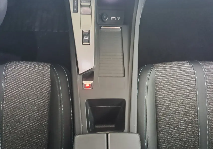 Vue plongeante sur la console centrale et les sièges gris foncé avec surpiqûres bleues de la Peugeot 308 2023.