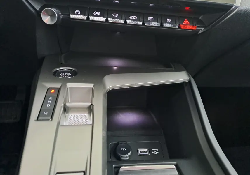 Vue rapprochée de la console centrale grise de la Peugeot 308 2023 avec bouton start, sélecteur de boîte auto et prises USB et 12V.