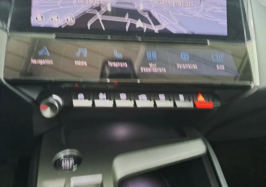 Vue rapprochée de la console centrale de la Peugeot 308 gris Artense 2023, avec écran tactile et boutons de commande éclairés.