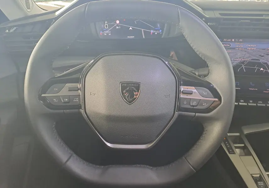 Vue rapprochée du volant cuir noir de la Peugeot 308 2023 avec logo lion et commandes intégrées.