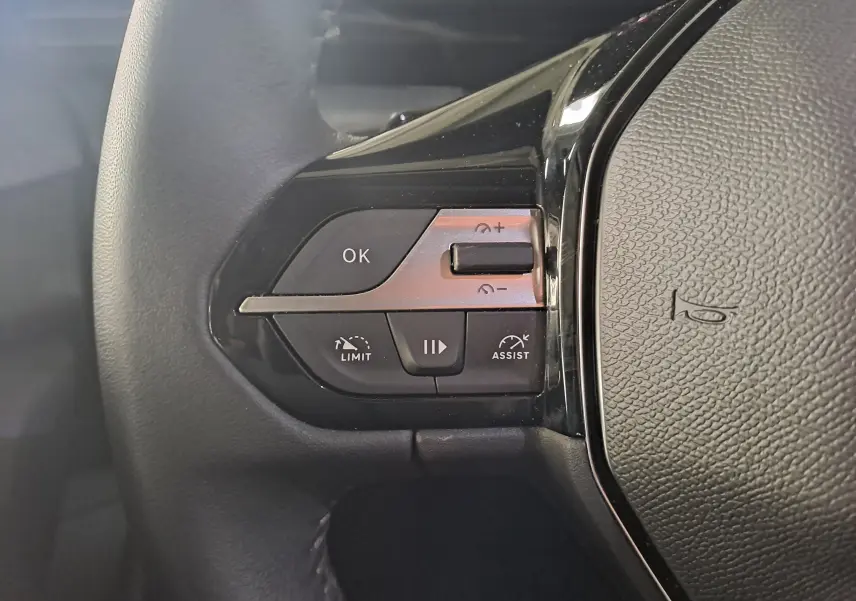 Gros plan sur les commandes de régulateur de vitesse au volant à gauche d'une Peugeot 308 gris Artense 2023.