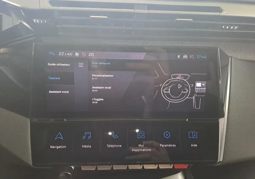 Écran tactile central de la Peugeot 308 2023 affichant le menu tutoriels avec icônes de navigation et médias.