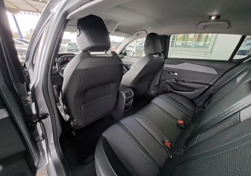 Vue intérieure arrière gauche de la Peugeot 308 gris Artense 2023, montrant les sièges arrière et la console centrale.