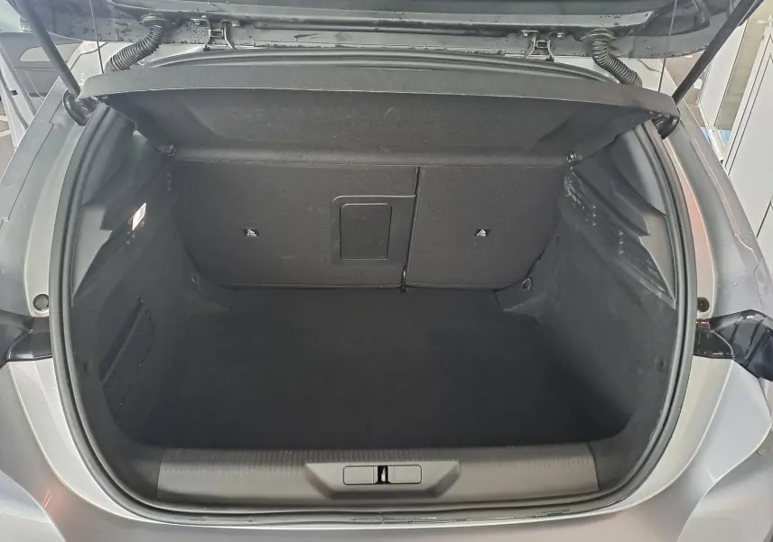 Coffre ouvert d'une Peugeot 308 gris Artense, vue arrière montrant un espace de chargement propre et spacieux.
