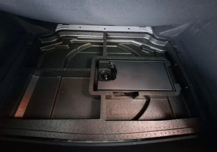 Coffre ouvert de la Peugeot 308 gris Artense 2023, vue plongeante sur le compartiment de rangement sous plancher.