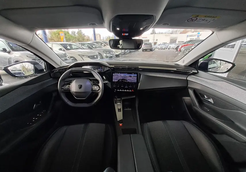 Vue intérieure avant de la Peugeot 308 gris Artense 2023, avec tableau de bord numérique et écran tactile central.