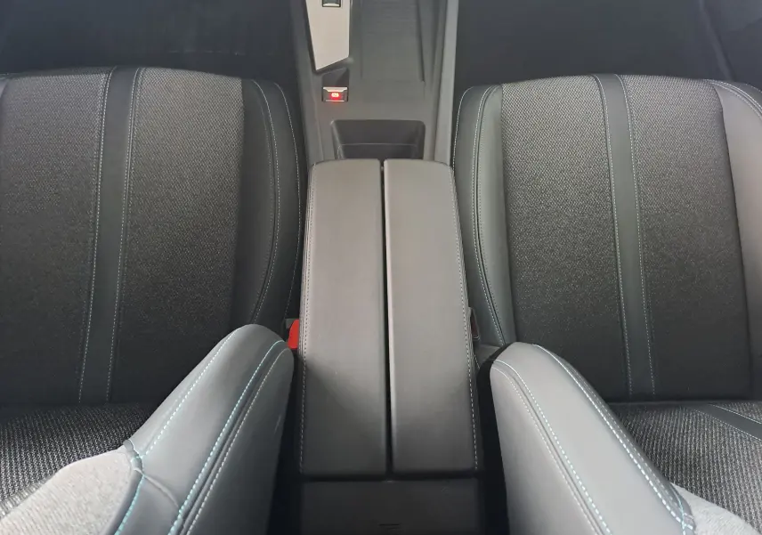 Vue rapprochée de l’intérieur gris avec accoudoir central et sièges avant du Peugeot 308 2023 finition Allure.