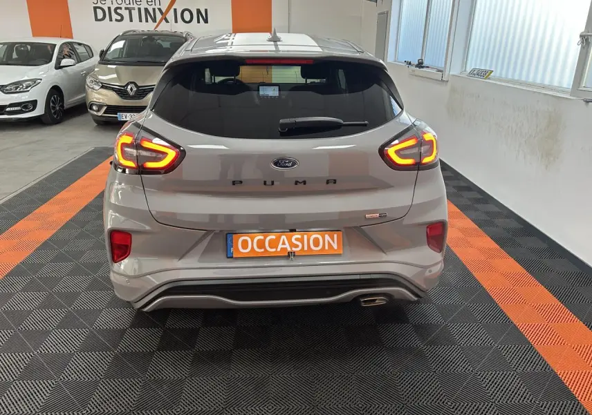 Vue arrière d'un Ford Puma gris métallisé avec feux arrière LED allumés dans un showroom.