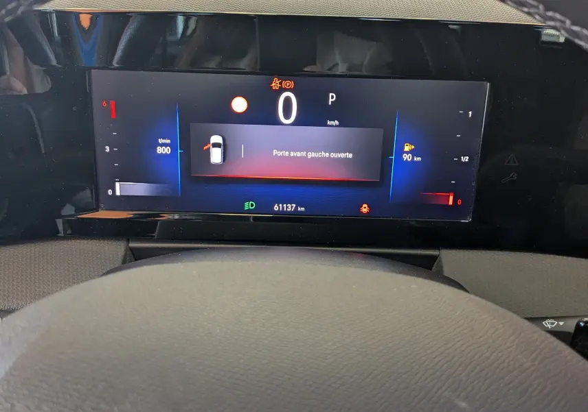 Vue rapprochée du tableau de bord numérique de l'Opel Astra bleu, affichant une porte avant gauche ouverte.