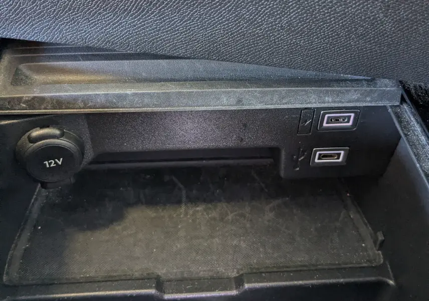 Gros plan sur la prise 12V et ports USB dans le rangement intérieur d'une Opel Astra bleu 2022 finition Elegance.