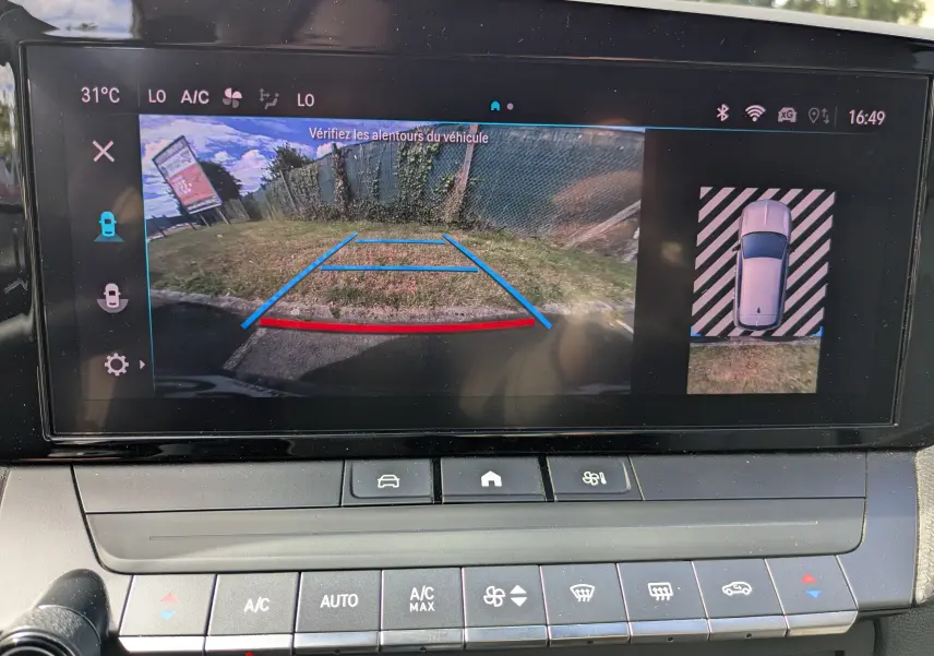 Vue de l'écran multimédia de l'Opel Astra bleu 2022 montrant la caméra de recul avec guidage de trajectoire coloré.