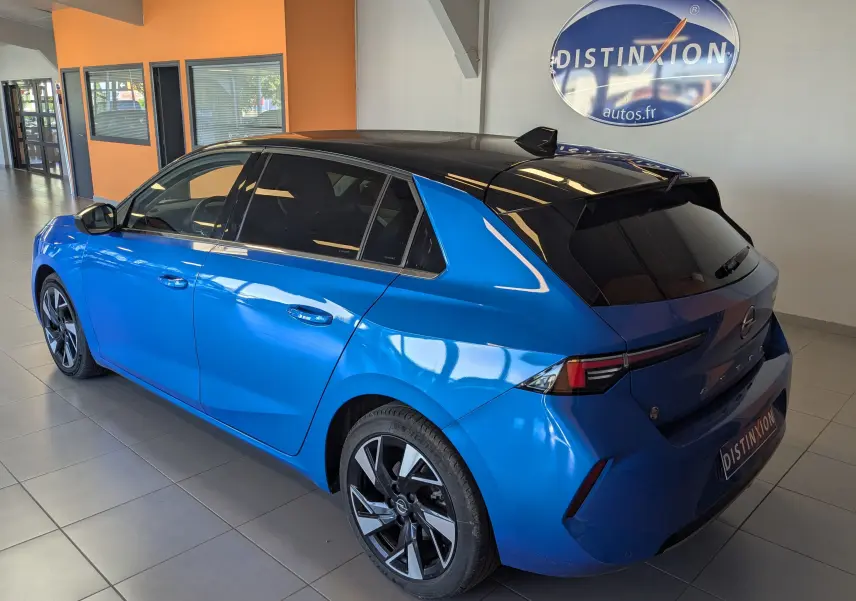 Opel Astra 1.5D 130ch finition Elegance bleu vue 3/4 arrière droit avec toit noir en intérieur showroom