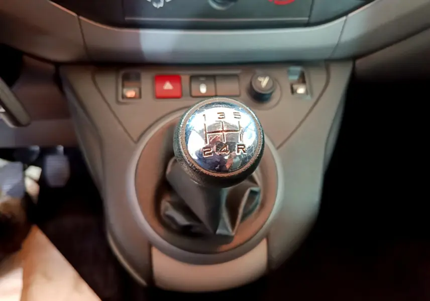 Gros plan sur le levier de vitesse manuel du Citroën Berlingo BlueHDi 75, entouré de commandes sur console grise.