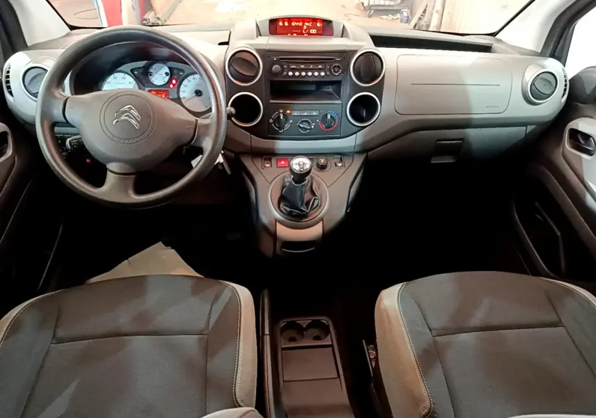Vue intérieure avant du Citroën Berlingo 2016 avec tableau de bord gris et volant noir à boîte manuelle.