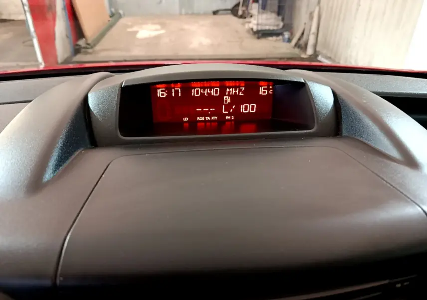 Affichage central du tableau de bord du Citroën Berlingo rouge, avec écran numérique rouge montrant l'heure et la température.