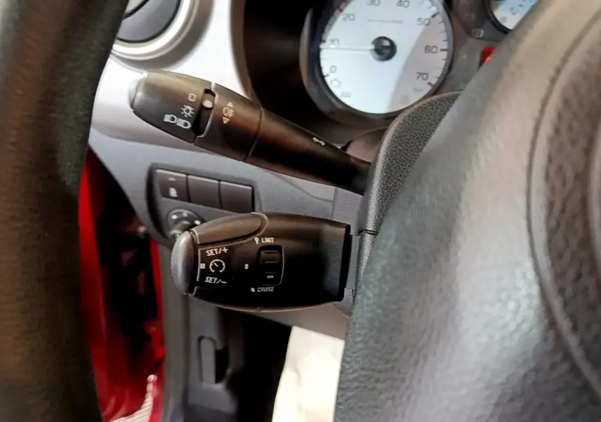 Gros plan sur les commandes de régulateur de vitesse et feux du tableau de bord du Citroën Berlingo rouge côté conducteur.