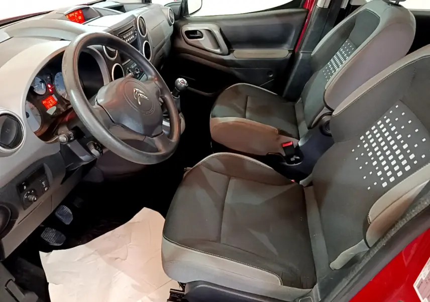 Vue intérieure côté conducteur du Citroën Berlingo rouge 2016, montrant sièges noirs et tableau de bord gris.