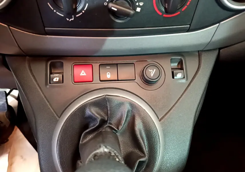 Gros plan sur la console centrale du Citroën Berlingo rouge 2016, montrant la commande de boîte manuelle et les boutons de verrouillage et warning.