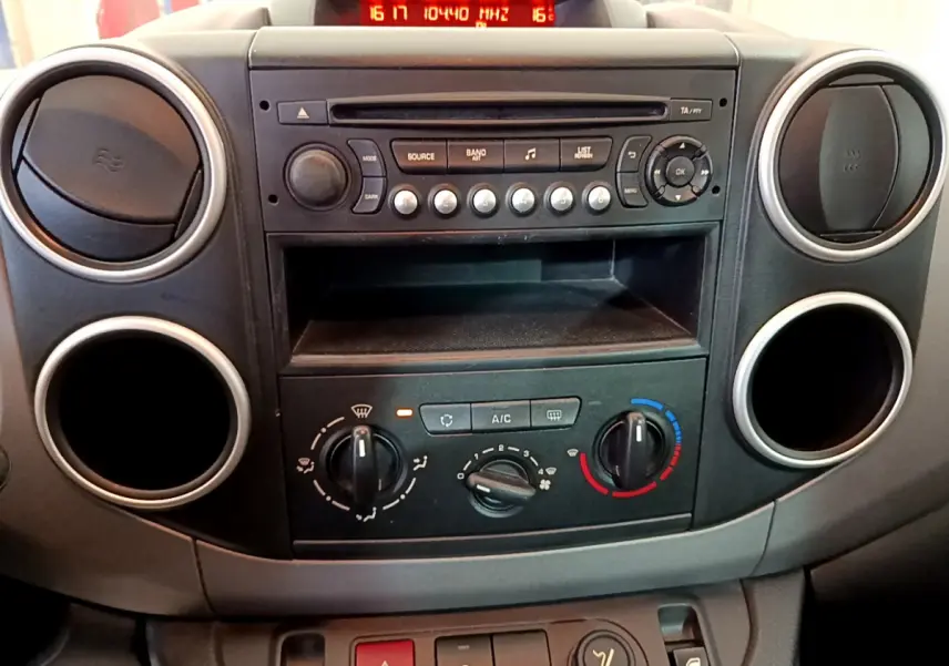 Tableau de bord central du Citroën Berlingo 2016, vue frontale montrant la radio, commandes de climatisation et aérateurs ronds noirs.