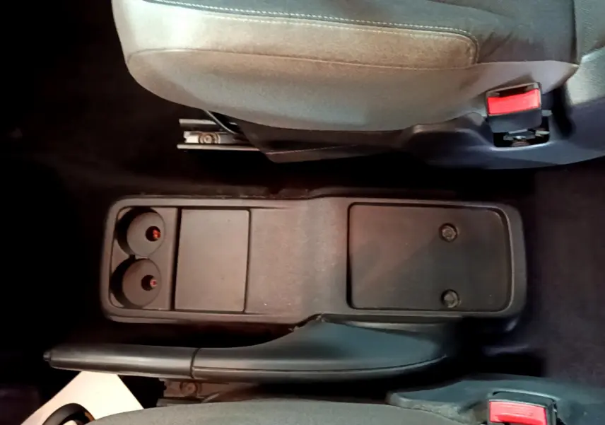 Vue plongeante sur la console centrale noire et frein à main entre les sièges avant gris du Citroën Berlingo rouge 2016.