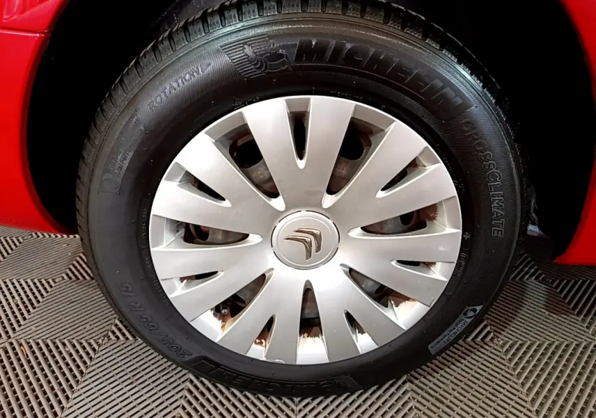 Gros plan sur la roue avant gauche rouge d'un Citroën Berlingo 2016 avec jante en enjoliveur argenté.