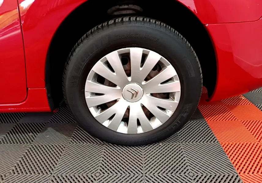 Gros plan sur la roue avant gauche rouge d’un Citroën Berlingo avec enjoliveur argenté et pneu Michelin.