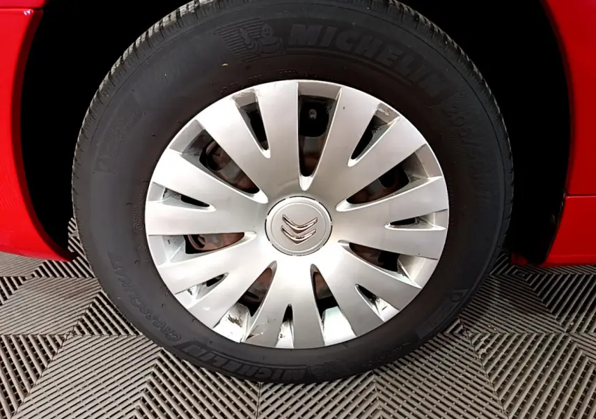 Gros plan sur la roue avant gauche du Citroën Berlingo rouge de 2016 avec enjoliveur argenté et pneu Michelin.