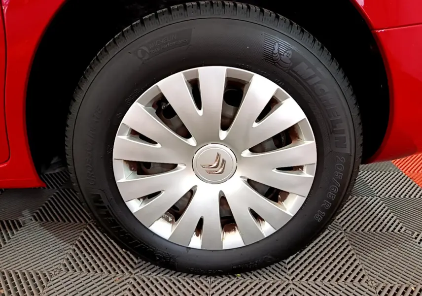 Gros plan sur la roue avant droite rouge d'une Citroën Berlingo 2016 avec enjoliveur argenté et pneu Michelin.
