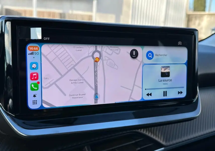 Écran tactile du tableau de bord de la Peugeot 208 blanc, affichant navigation et musique en vue rapprochée.