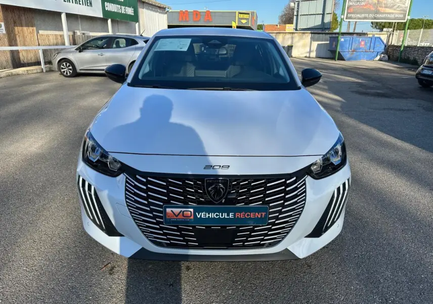 Vue avant d'une Peugeot 208 Hybrid 110 e-DCS6 Allure blanche avec calandre noire et feux LED distinctifs.