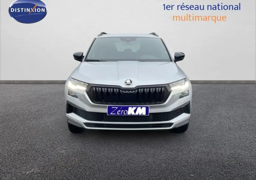 Vue frontale d'un Skoda Karoq argent 2025 avec calandre noire et phares allumés sur fond neutre.