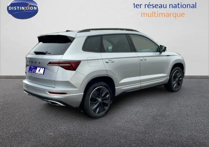 Vue 3/4 arrière droite d'un Skoda Karoq argent avec barres de toit et vitres arrière teintées.