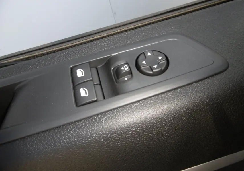 Gros plan sur les commandes de réglage des rétroviseurs et des vitres électriques côté conducteur du Peugeot Expert blanc 2023.