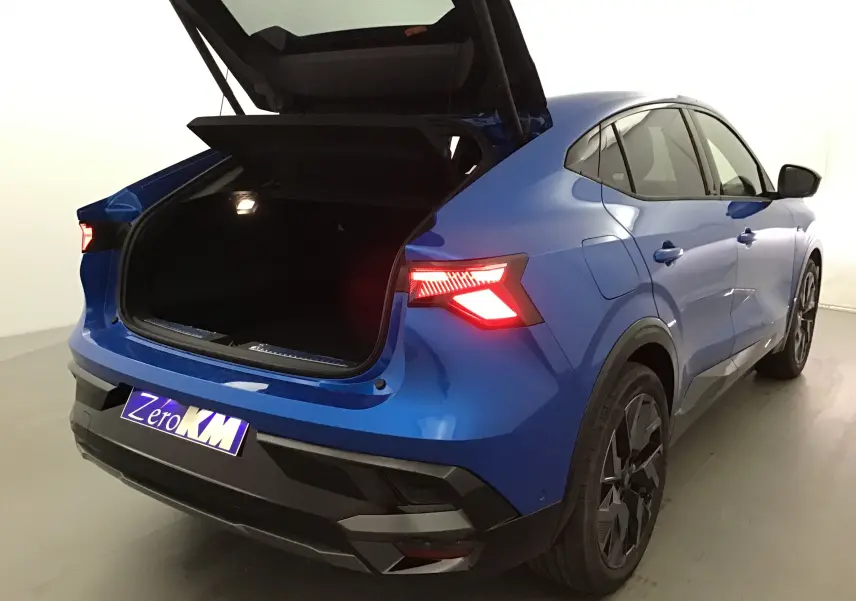 Vue 3/4 arrière droite d'une Renault Rafale bleu sommet avec coffre ouvert et feux arrière LED allumés.