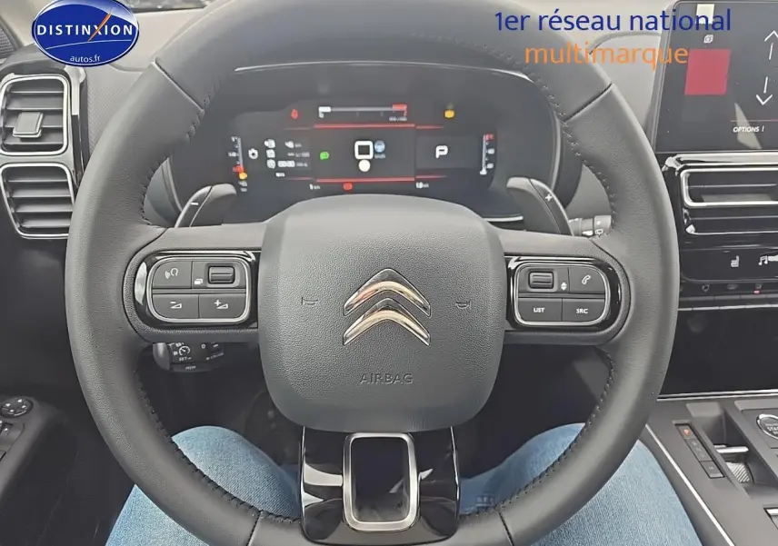 Vue rapprochée du volant cuir noir du Citroën C5 Aircross 2025 avec tableau de bord digital et commandes intégrées.