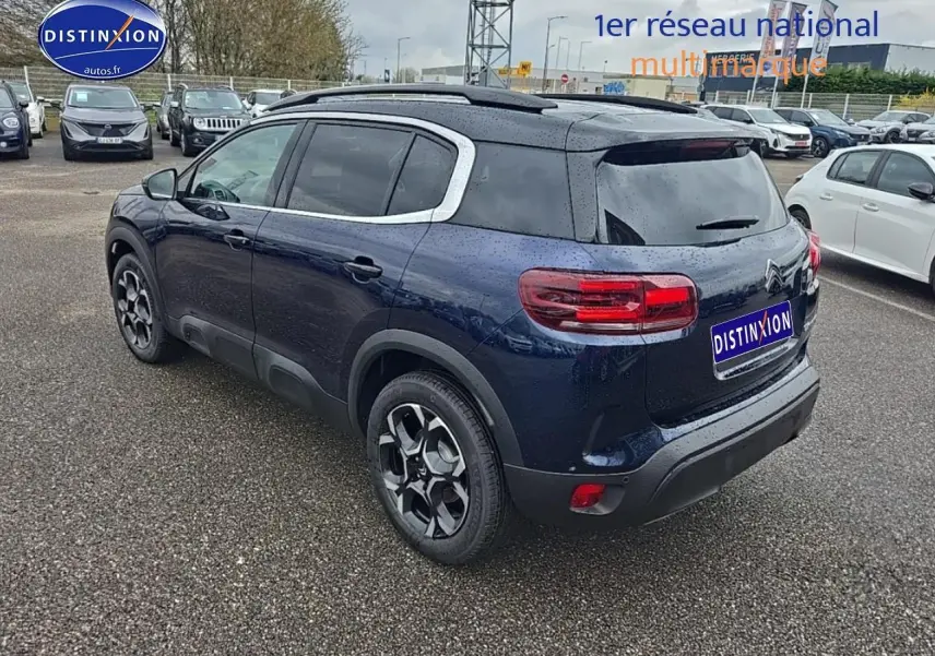 Vue 3/4 arrière droite d'un Citroën C5 Aircross bleu eclipse avec toit noir et jantes alu 18 pouces sur parking.